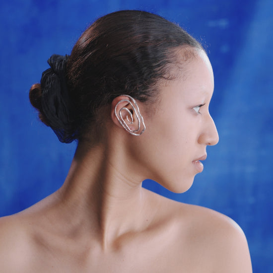 Black female model demonstrate how to wearing moksha silver ear cuff.